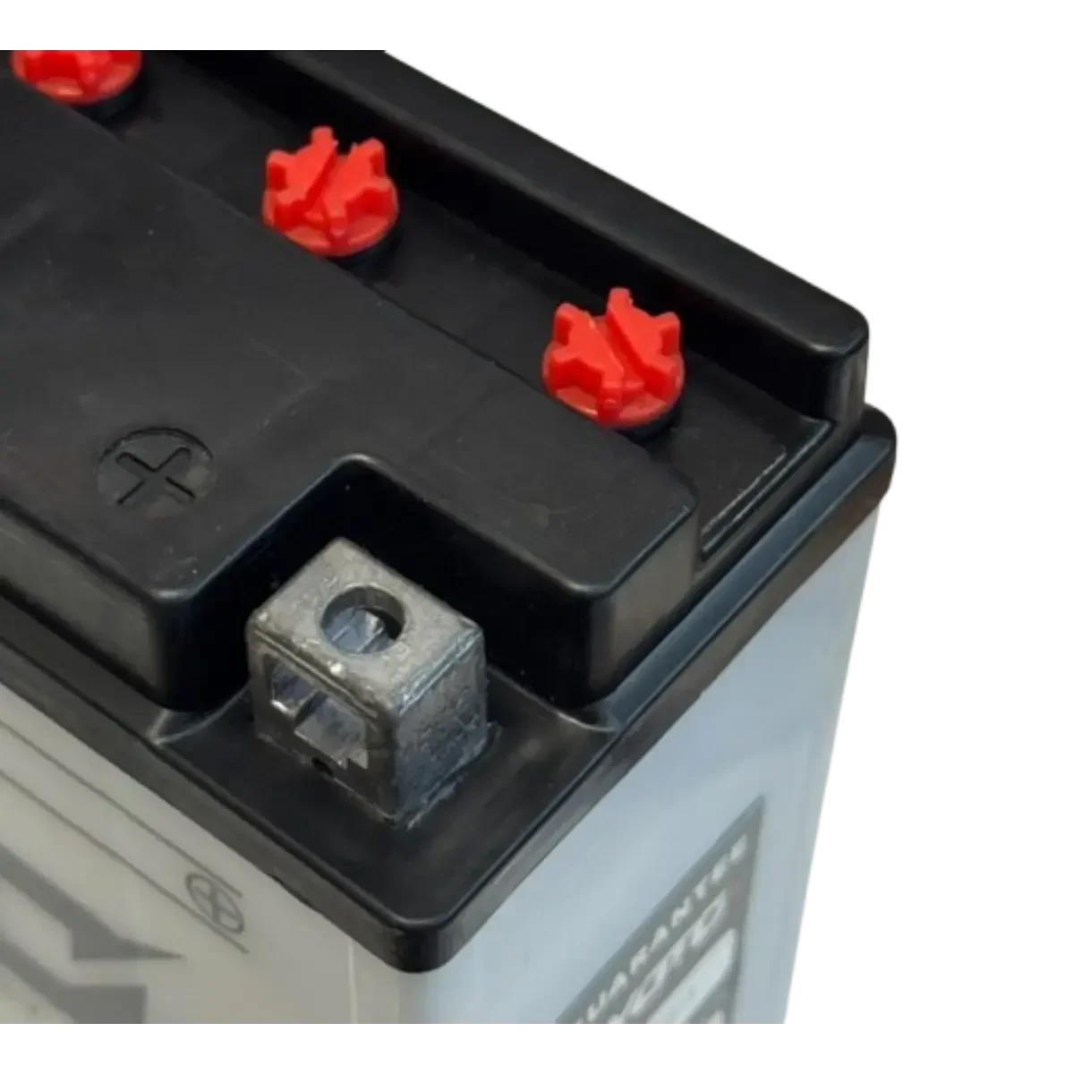 Détail du dessus d'une batterie moto KYOTO YB16AL-A2 avec bouchons rouges et borne positive.